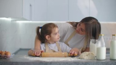 Anne kızının para kazanmasına yardım ediyor. Anne ve küçük kızı kurabiye yapmak için para saçıyorlar. merdane kullanarak ve bisküvi yaparak.