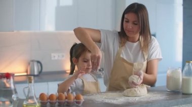 Ellerinle yoğururken hamurun üzerine un koy. Kızımla bir pizzayı boşaltıyorum. Sevgi dolu anne ve kız, aile tarifine göre birlikte yemek pişirir.