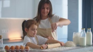 Anne kızının para kazanmasına yardım ediyor. Anne ve küçük kızı kurabiye yapmak için para saçıyorlar. merdane kullanarak ve bisküvi yaparak.