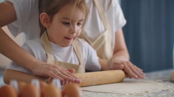 Anne kızının para kazanmasına yardım ediyor. Anne ve küçük kızı kurabiye yapmak için para saçıyorlar. merdane kullanarak ve bisküvi yaparak. — Stok video