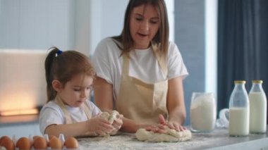 Anne ve kızı mutfakta hamur kalıbıyla yemek pişiriyorlar. Anne ve kızı kalp şeklinde hamur kalıbı tutuyorlar. Hamuru ellerinle şekillendir, pizza ya da turta için kuru sıkı yap, kurabiye yap.