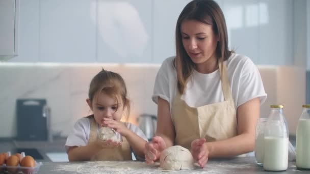 Moeder en dochter koken met deegvorm in de keuken. Moeder en dochter met hartvormige deegvorm. Snijd het deeg met je handen om losse flodders te maken voor pizza of taart, koekjes — Stockvideo