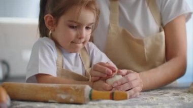 Anne ve kızı mutfakta hamur kalıbıyla yemek pişiriyorlar. Anne ve kızı kalp şeklinde hamur kalıbı tutuyorlar. Hamuru ellerinle şekillendir, pizza ya da turta için kuru sıkı yap, kurabiye yap.