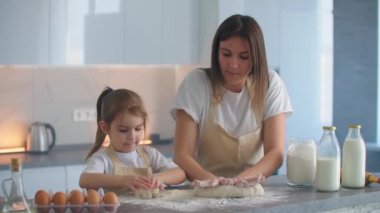 Kadın ve kız mutfakta yumurta çırpıyor. Kız ve anne birlikte yemek pişiriyorlar.