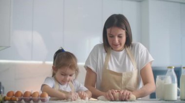 Anne ve kızı mutfakta hamur kalıbıyla yemek pişiriyorlar. Anne ve kızı kalp şeklinde hamur kalıbı tutuyorlar. Hamuru ellerinle şekillendir, pizza ya da turta için kuru sıkı yap, kurabiye yap.