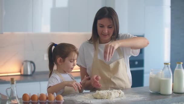 Мама учит дочь делать заготовки для пиццы или торта, сделанные руками из теста. Руки мешают тесто с маленькой дочерью . — стоковое видео
