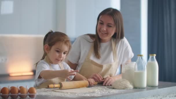Mamá ayudando a su hija a sacar dinero. Mamá y su hijita sacan la masa para hacer galletas. usando el rodillo y haciendo galletas . — Vídeos de Stock
