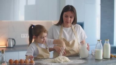 Kız ve annesi mutfakta birlikte yemek pişirir ve hamuru elleriyle şekillendirirler. Pizzayı ellerinle yoğur..