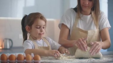 Anne ve kızı, akşam pastası yapmak için hamuru elleriyle şekillendiriyorlar. Birlikte pişmiş şeffaf yemek. Küçük kızıma krep, aladi, pizza, turta ve kurabiye yapmayı öğretiyorum..