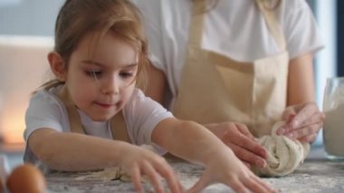 Anne ve kızı mutfakta hamur kalıbıyla yemek pişiriyorlar. Anne ve kızı kalp şeklinde hamur kalıbı tutuyorlar. Hamuru ellerinle şekillendir, pizza ya da turta için kuru sıkı yap, kurabiye yap.