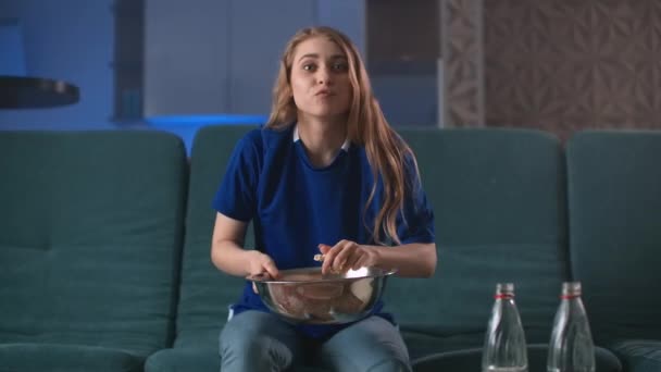 Portretfoto van de jonge knappe vrouw die voor de tv op de bank zit met popcorn en bier terwijl ze sport kijkt en zijn team verliest. Binnenshuis. — Stockvideo