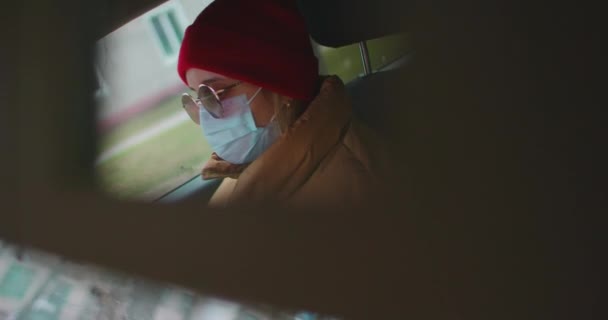 Een vrouw met een beschermend masker rijdt in een auto op de weg. Achteruitkijkspiegelreflectie. Veilig reizen. — Stockvideo