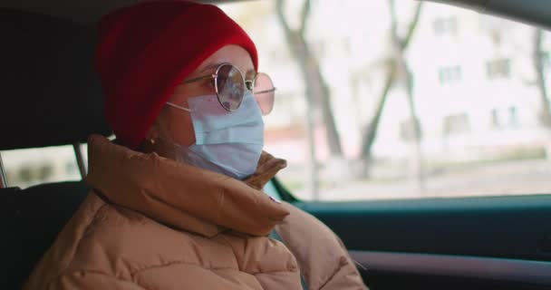 Rallentatore: donna caucasica europea che guida un'auto e indossa una maschera medica chirurgica bianca come protezione contro il coronavirus e l'influenza . — Video Stock