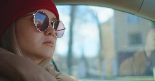 Een vrouw in een auto met een zonnebril. Een jonge vrouw met een bril die een auto bestuurt op de landweg, van binnenuit bekeken. Heldere zon schijnt achter ons — Stockvideo