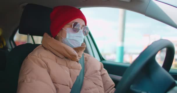 Zpomalený pohyb: Mladá žena v ochranné sterilní lékařské obličejové masce v autě, pandemický koronavirus koncept. — Stock video