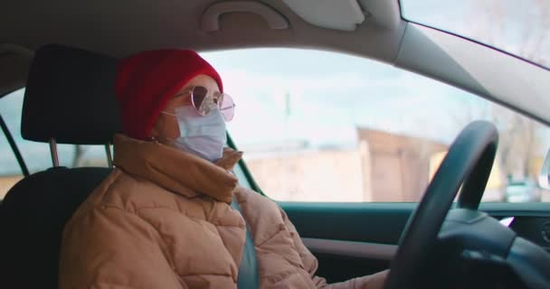 Zpomalení: Samostatná izolace a jízda osobními automobily během karantény a pandemií. Koronavirus a epidemie Mladá žena nosit masku a řízení auta. — Stock video