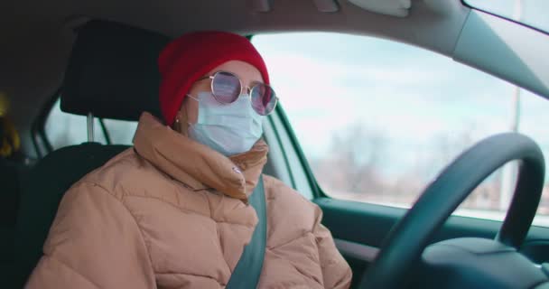 Blanke vrouw draagt gezichtsmasker tijdens het rijden tijdens de extreme coronavirus uitbraak. Vrouw met een beschermend masker rijdt door de stad tijdens de COVID19 pandemie — Stockvideo