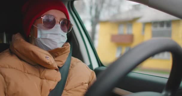 Slow-motion: Kaukasische Europese vrouw die een auto bestuurt en een wit chirurgisch gezichtsmasker draagt als bescherming tegen coronavirus en griep. — Stockvideo