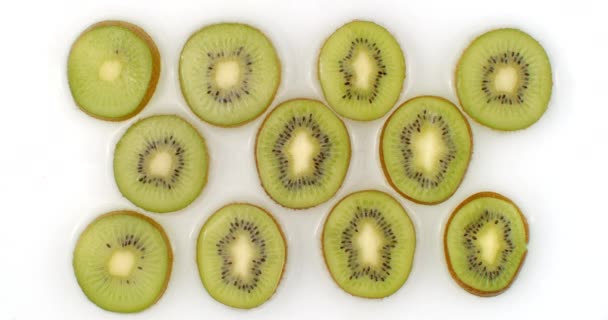 Op een witte achtergrond worden gesneden kiwi 's bestrooid met water. Waterdruppels sappige kiwi — Stockvideo