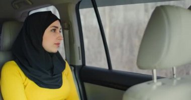 Yolcu koltuğunda oturan tesettürlü genç Müslüman kadın. Müslüman kadınlar günü arka koltukta hayal kuruyor. Tesettürlü genç bir kadın pencereden dışarı bakar..