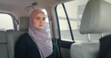 Yolcu koltuğunda oturan tesettürlü genç Müslüman kadın. Müslüman kadınlar günü arka koltukta hayal kuruyor. Tesettürlü genç bir kadın pencereden dışarı bakar..