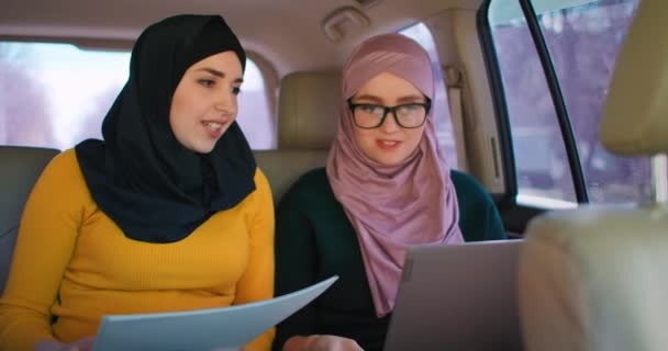 Young Arabian businesswomen with two laptops on the back seats of car. Teamwork on the move 2 Modern Muslim business woman in automobile. Two Saudi Businesswoman Colleagues Working With Laptop In Car — Stock Video