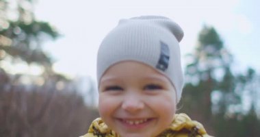 Mutlu çocuk parktaki kameraya doğru ağır çekimde koşuyor. Küçük çocuk ormanda koşuyor. Mutlu gülen çocuk ormanda koşup duygusal oyunlar oynuyor.