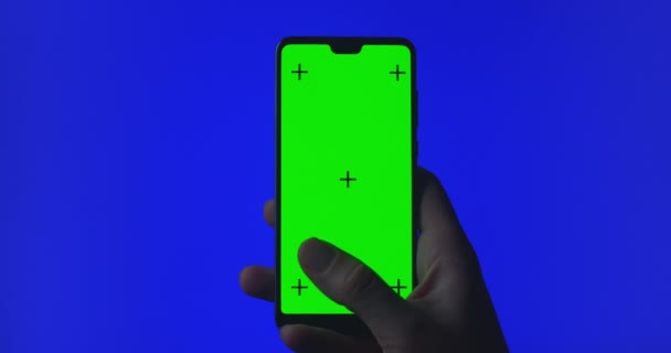 Eldeki telefon yeşil arka planda izole edilmiş. Telefon ekranı - yeşil krom anahtar, arka plan mavi krom anahtar. Çerçeve — Stok video