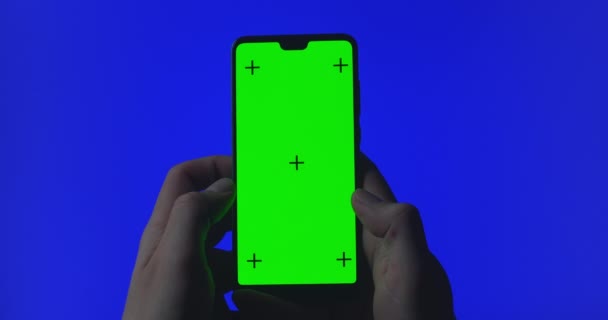 Yeşil ekranda krom anahtarı gösteren akıllı telefon kullanılıyor. Görüntü, kaydırma, video içeriği üzerinden yeşil ekran inblue arkaplan kaydırmalı akıllı telefon kullanan kız. İzleme işaretleri — Stok video