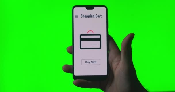 Um telefone celular nas mãos de uma pessoa com uma animação na tela sobre compra e pagamento online. clique no botão comprar agora. A enviar dinheiro via Internet banking. Fundo verde para chromakey . — Vídeo de Stock