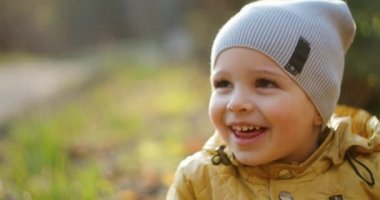 Ağır çekim: Sarı Ceketli Genç Güneş Ormanında Otururken Etrafındaki Dünyayı Keşfeder. Ormanda eğlen ve gül. Özgür neşeli çocukluk