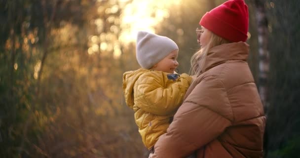 Mutlu aile annesi ve oğlu gün batımında parkta oynuyorlar. Aile değerleri kavramı. Aktif yaşam tarzı. Bir kadın kış parkında bir çocukla yürüyor. Çocuk annesiyle vakit geçiriyor.. — Stok video