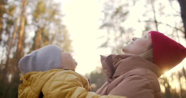スローモーションでのレンズフレア:公園の夢と愛の抱擁と一緒に時間を過ごすの黄色のジャケットの若い母親と息子。幸せな子供時代。自然の中で家族と過ごす時間. — ストック動画