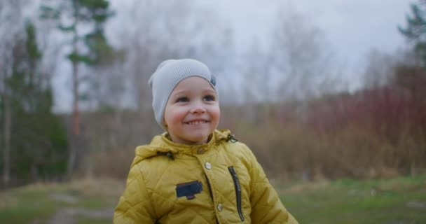スローモーションのレンズフレア:秋の公園を走る幸せな赤ちゃん。秋の散歩で遊んでいる小さな子供。黄金の葉を持つ秋の森。黄金の葉を持つ秋の森 — ストック動画