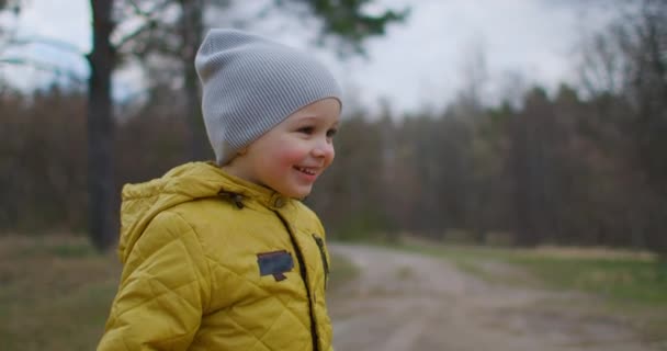 Lens Flare in Slow Motion: Buon bambino che corre nel parco autunnale. Bambino che gioca sulla passeggiata autunnale. Foresta autunnale con foglie dorate. Foresta autunnale con foglie dorate — Video Stock