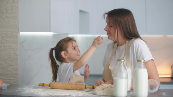 Filha e mãe em casa na cozinha em aventais entrar e se divertir dar cinco e polvilhar com farinha — Vídeo de Stock