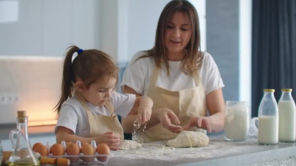 Pequeña hija ayudante ayuda a su madre a preparar masa casera en la cocina — Vídeos de Stock