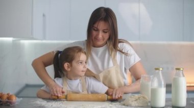 Küçük yardımcı kız annesine mutfakta ev yapımı hamur hazırlamasında yardım eder.