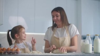 Kız ve anne mutfakta önlüklerle eğleniyor, eğleniyor ve eğleniyorlar. Beşe kadar sayıp, un serpiyorlar.