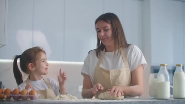 Hija y madre en casa en la cocina en delantales disfrutar y divertirse dar cinco y espolvorear con harina — Vídeos de Stock