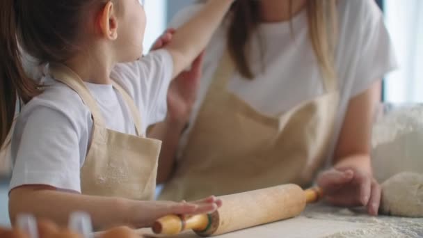 Дочка і мати вдома на кухні в фартухах насолоджуються і розважаються дайте п'ять і посипте борошном — стокове відео