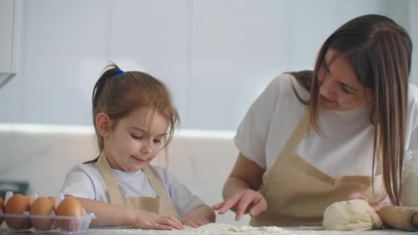 Дочь и мать дома на кухне в фартуках баловать и веселиться дать пять и посыпать мукой — стоковое видео
