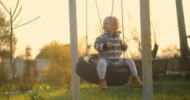 En långsam rörelse glad liten pojke svänger på en gunga. — Stockvideo