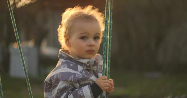 スイングで彼の時間を楽しんでかわいい男の子のスローモーションショット。スイングで彼の時間を楽しんでかわいい男の子のスローモーションショット. — ストック動画