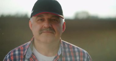 Düşünceli yaşlı çiftçinin portresi kameraya bakıyor. Kıdemli Çiftçi gülümsüyor. Ağır çekim. Kameraya gülümseyen sakallı, beyaz, yakışıklı genç adama yaklaş.