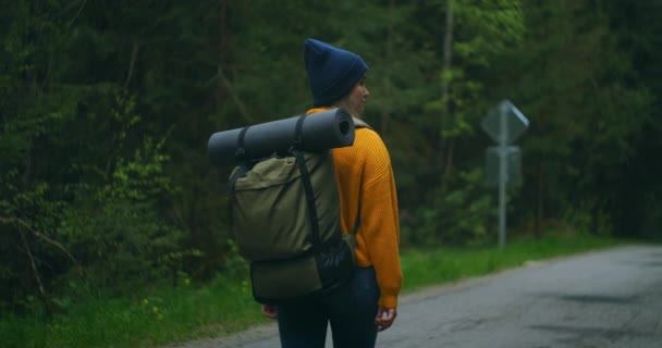 スローモーション:秋に森の中を歩く若い女性。バックパックを木に取ってアクティブな健康的な白人女性。フォレストリアビュー、レジャー、バイオツーリズム、ハイキングに沿って散歩を持つ女性旅行者 — ストック動画