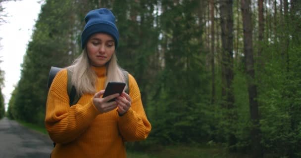 Chica con mochila usando Smartphone Gps. Mujer Senderismo en el bosque y escribir mensaje en el teléfono inteligente. Caminadora solista usando un teléfono inteligente. Senderista toma foto de teléfono inteligente de las montañas y el bosque. — Vídeo de stock