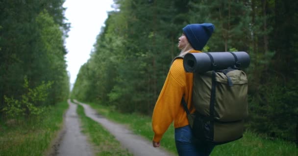 Slow motion: Ung kvinna Vandring i skogen på hösten. Aktiva friska kaukasiska kvinna med en ryggsäck tar i trä. Kvinnlig resenär med promenader längs skogen bakre vy, fritid, bio-turism, Vandring — Stockvideo