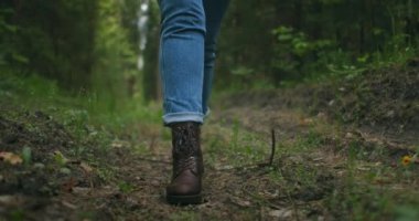 Ağır çekimde dik arazide yürüyen kadınların bacaklarını kapatın. Yürüyüş Botları Sonbahar Yolu 'nda yürüyor. Kadın ayak izleri sonbahar günü açık havada, ormanlık alanda yürüyor.