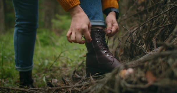 Kobieta na wycieczce do lasu wiąże sznurowadła. Buty turystyczne w lesie — Wideo stockowe